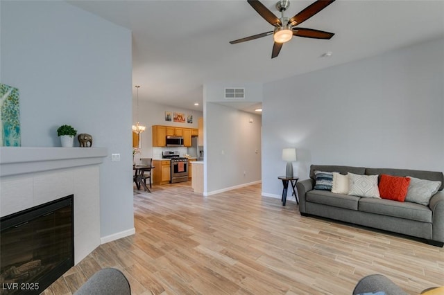 2305 W Horizon Ridge Pkwy Unit 3713, Henderson, NV 89052 - living area with ceiling fan with notable chandelier, light wood-type flooring, a tiled fireplace, baseboards, and visible vents