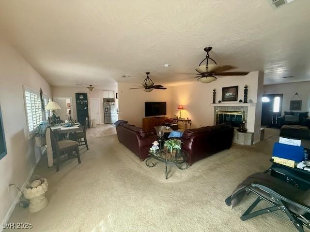 10561 Rancho Destino Rd, Las Vegas, NV 89183 - carpeted living area with ceiling fan, a glass covered fireplace, a wealth of natural light, and visible vents