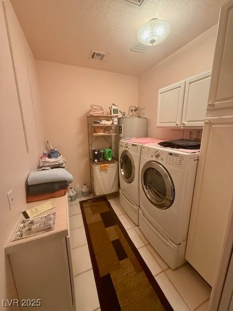 10561 Rancho Destino Rd, Las Vegas, NV 89183 - laundry area with washer and clothes dryer, a textured ceiling, cabinet space, water heater, and light tile patterned floors