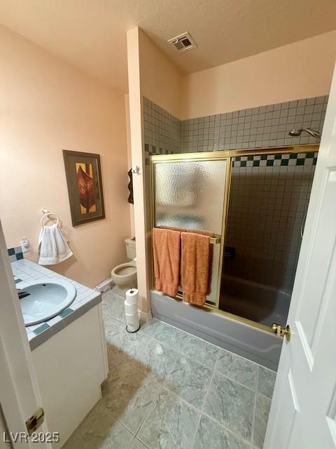 10561 Rancho Destino Rd, Las Vegas, NV 89183 - bathroom featuring visible vents, tile patterned flooring, vanity, toilet, and combined bath / shower with glass door