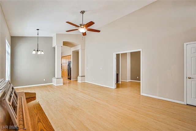 1742 Sand Storm Dr, Henderson, NV 89074 - unfurnished living room featuring baseboards, arched walkways, light wood finished floors, and ceiling fan with notable chandelier