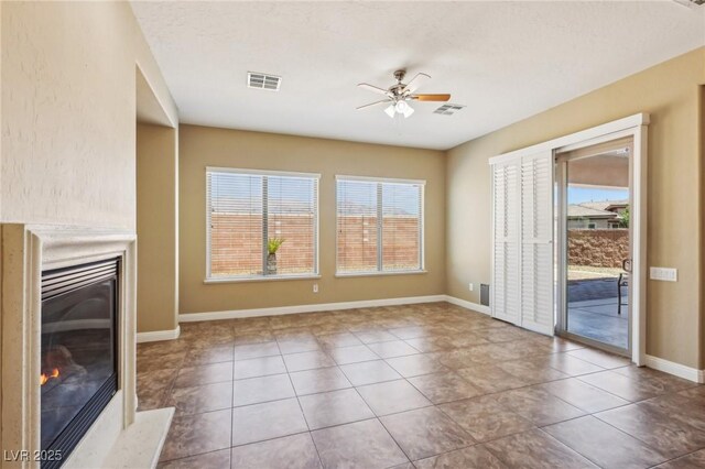 3904 Redbreast Ln, North Las Vegas, NV 89084 - unfurnished living room with tile patterned flooring, a ceiling fan, a glass covered fireplace, and visible vents