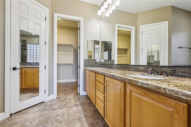 3904 Redbreast Ln, North Las Vegas, NV 89084 - bathroom featuring a walk in closet, backsplash, a sink, and double vanity