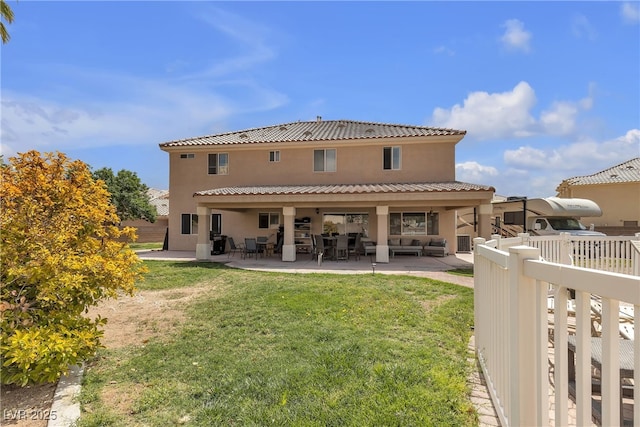 rear view of property featuring a lawn, a patio, stucco siding, and an outdoor living space
