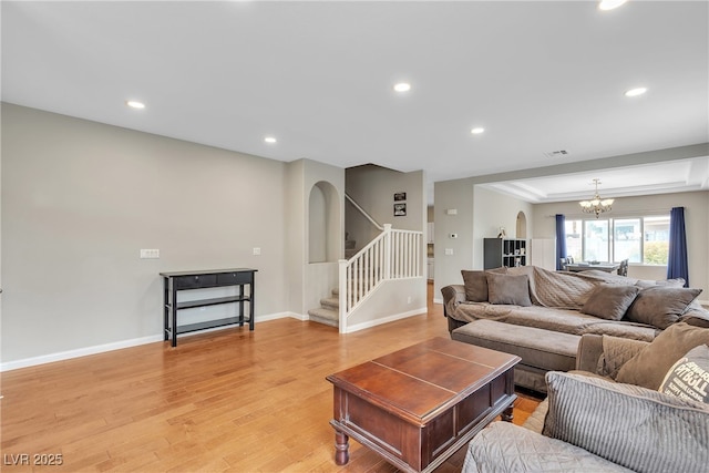 living area with light wood-type flooring, a chandelier, recessed lighting, and stairs