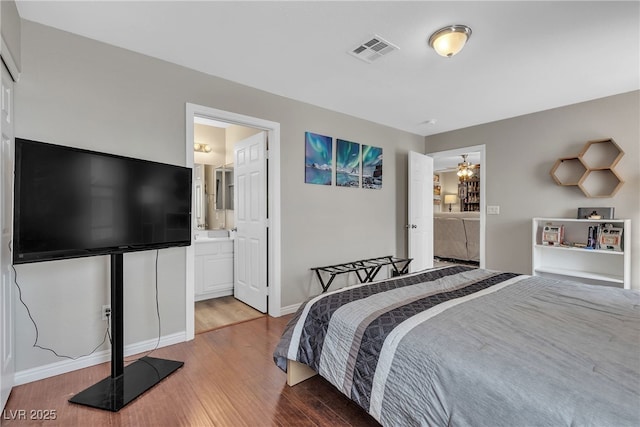 bedroom with visible vents, light wood finished floors, baseboards, and connected bathroom