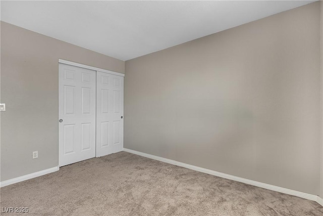 unfurnished bedroom with baseboards, carpet flooring, and a closet