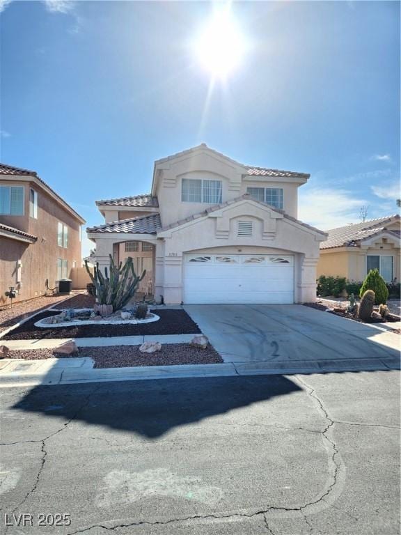 traditional-style home with stucco siding, a tiled roof, a garage, and concrete driveway
