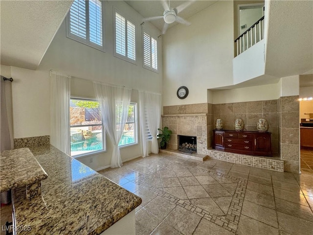 1105 Enderly Ln, Las Vegas, NV 89144 - unfurnished living room with a towering ceiling, a ceiling fan, plenty of natural light, a tile fireplace, and inlaid floor details
