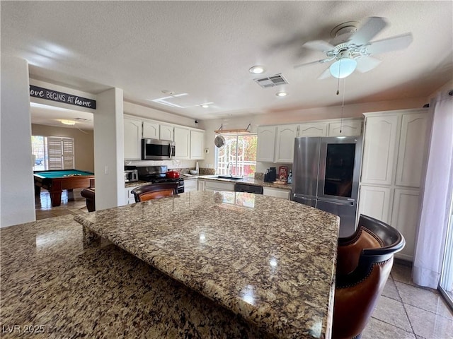 1105 Enderly Ln, Las Vegas, NV 89144 - kitchen with black appliances, white cabinetry, dark stone countertops, ceiling fan, and a textured ceiling