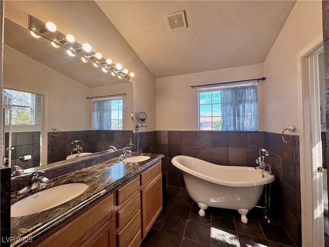 1105 Enderly Ln, Las Vegas, NV 89144 - full bathroom with vaulted ceiling, tile walls, plenty of natural light, a soaking tub, and double vanity