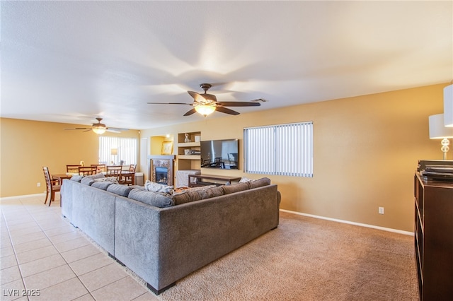 living room with light tile patterned flooring, a fireplace, a ceiling fan, baseboards, and visible vents