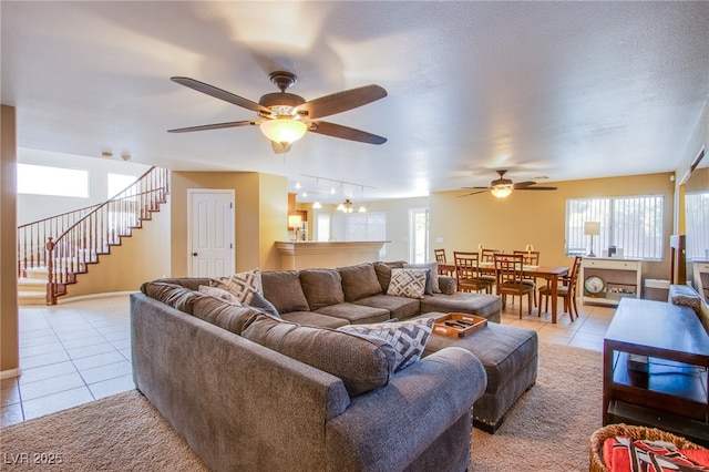 living room with ceiling fan, light tile patterned flooring, stairway, and a healthy amount of sunlight