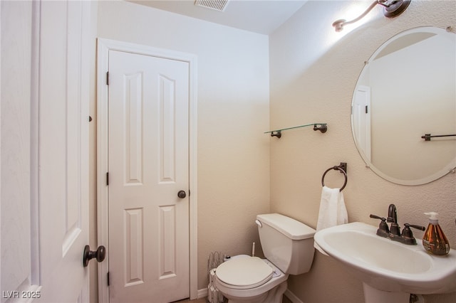 bathroom with toilet, visible vents, and a sink