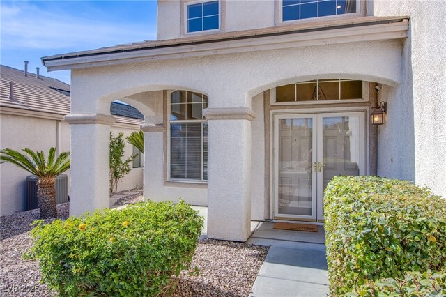 doorway to property with central AC unit, stucco siding, and french doors