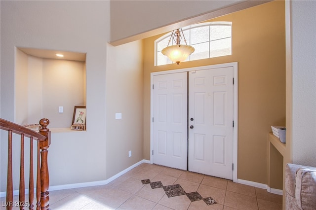 entryway featuring baseboards, stairs, a high ceiling, and light tile patterned flooring