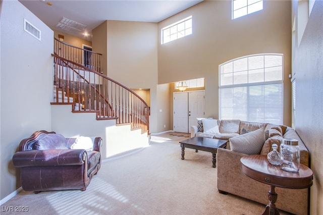 carpeted living area with stairway, baseboards, a high ceiling, and visible vents