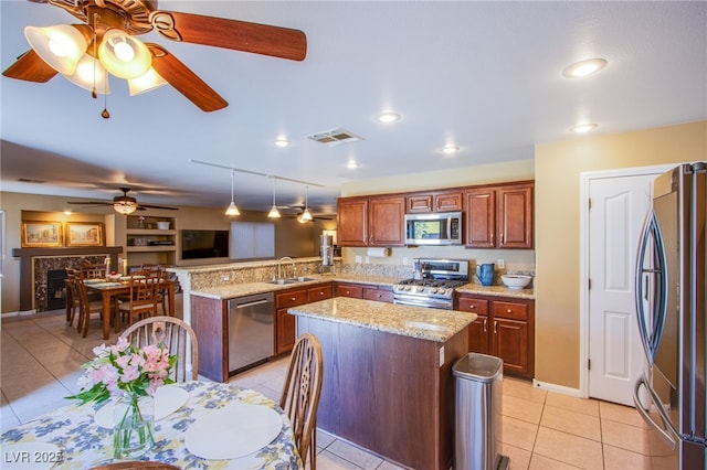 kitchen featuring a sink, a peninsula, a ceiling fan, appliances with stainless steel finishes, and light tile patterned floors