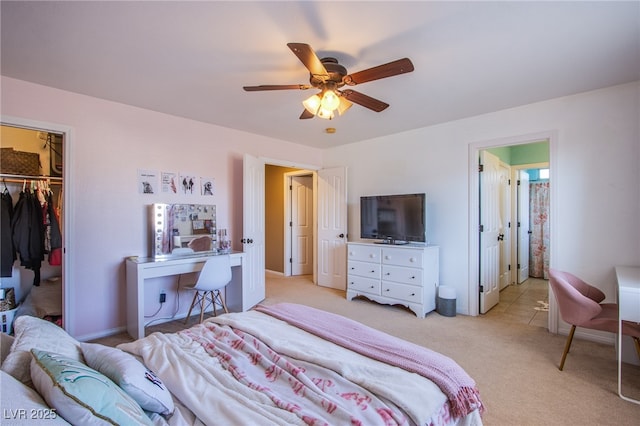bedroom featuring a ceiling fan, light carpet, a walk in closet, and a closet