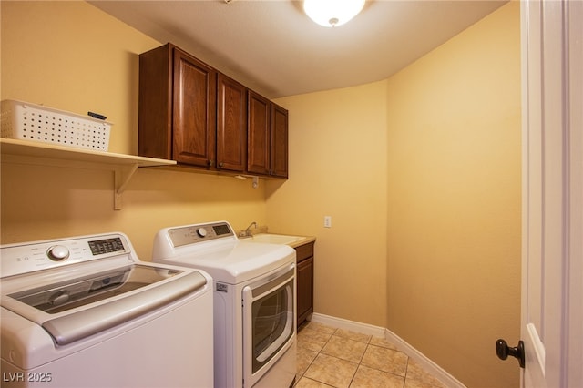 clothes washing area featuring baseboards, a sink, cabinet space, independent washer and dryer, and light tile patterned floors