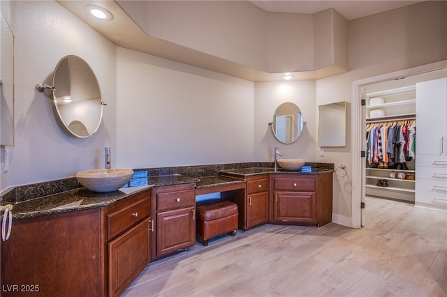 full bath featuring vanity, a walk in closet, and wood finished floors