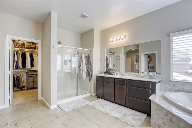 bathroom featuring a walk in closet, tile patterned flooring, vanity, visible vents, and a stall shower
