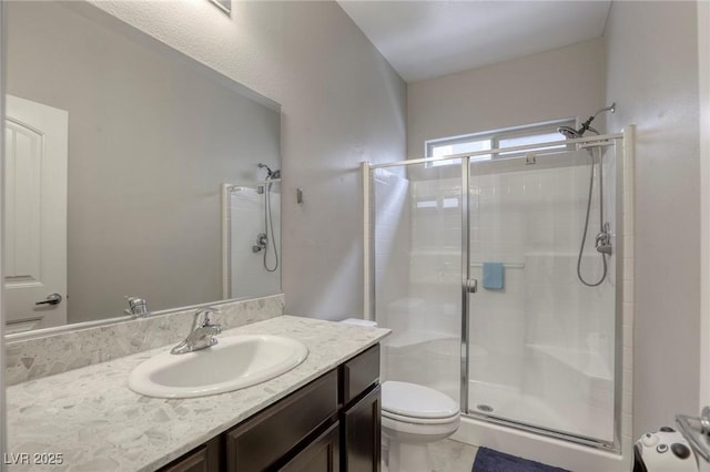 bathroom with vanity, a shower stall, and toilet