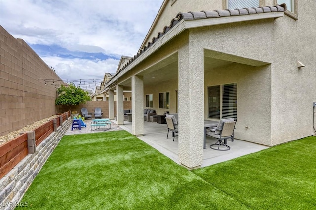 rear view of property with a fenced backyard, a patio, stucco siding, and a yard