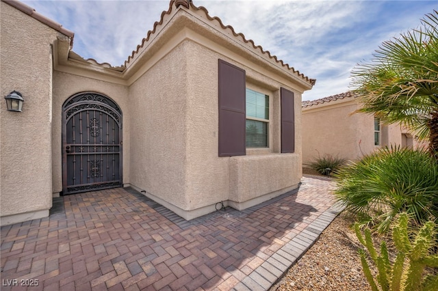 view of exterior entry with stucco siding and a tile roof