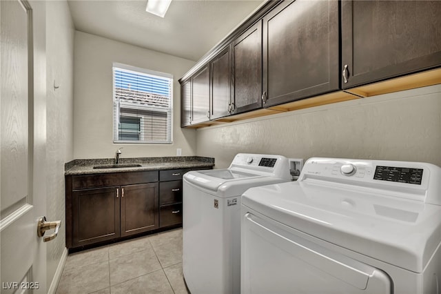laundry area with a sink, light tile patterned floors, washer and dryer, cabinet space, and baseboards