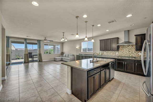 kitchen with visible vents, wall chimney range hood, a sink, a wealth of natural light, and appliances with stainless steel finishes
