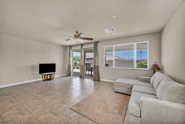 living area featuring plenty of natural light, visible vents, ceiling fan, and light tile patterned flooring