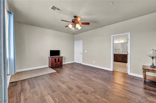unfurnished living room with dark wood-type flooring, visible vents, a ceiling fan, and baseboards