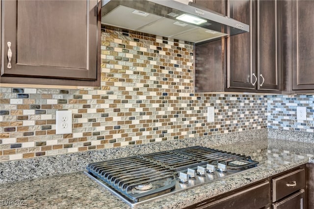 kitchen featuring wall chimney exhaust hood, tasteful backsplash, dark brown cabinets, and stainless steel gas stovetop