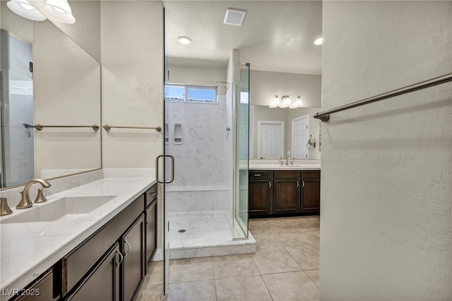 full bathroom featuring tile patterned flooring, visible vents, a sink, and a stall shower