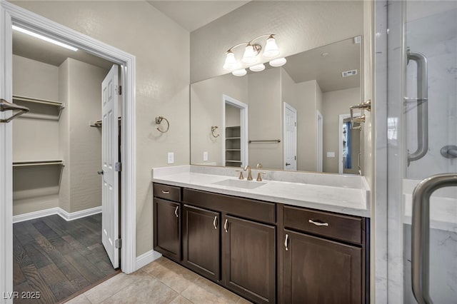 bathroom with a spacious closet, baseboards, vanity, and visible vents