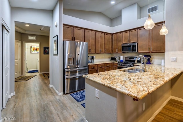 8036 Literature Ct, Las Vegas, NV 89113 - kitchen with light stone counters, visible vents, light wood-style floors, a peninsula, and appliances with stainless steel finishes