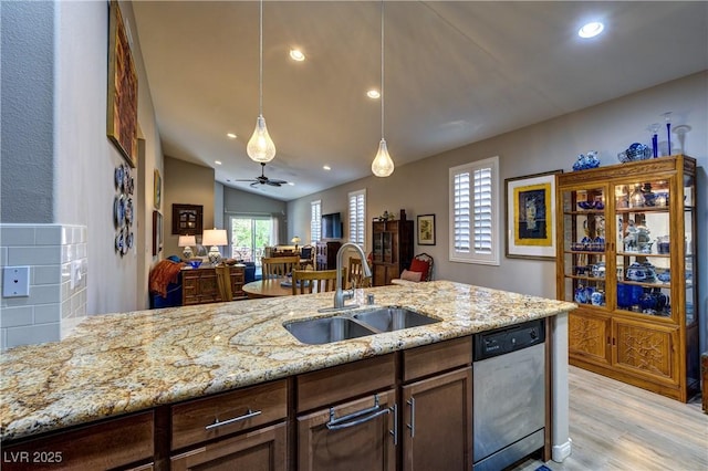8036 Literature Ct, Las Vegas, NV 89113 - kitchen featuring light wood finished floors, stainless steel dishwasher, a sink, light stone counters, and decorative light fixtures