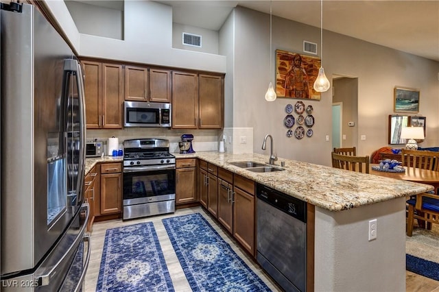8036 Literature Ct, Las Vegas, NV 89113 - kitchen featuring light stone counters, a sink, a peninsula, appliances with stainless steel finishes, and visible vents