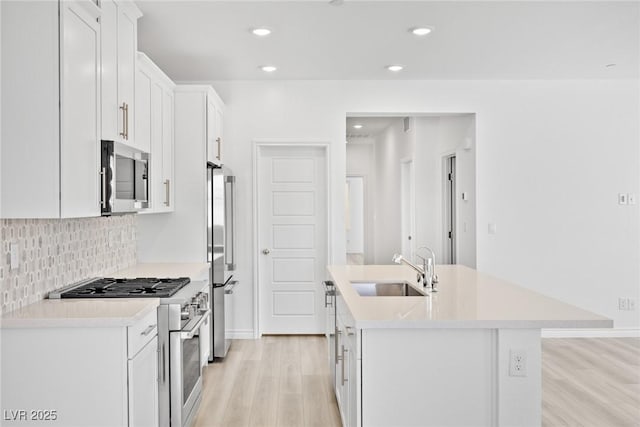 600 N Carriage Hill Dr Unit 2098, Las Vegas, NV 89138 - kitchen with white cabinets, stainless steel appliances, a kitchen island with sink, a sink, and light wood-type flooring