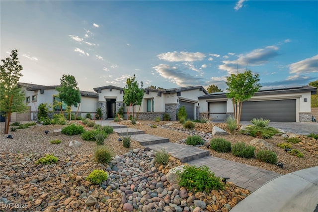 view of front of house featuring solar panels, driveway, stone siding, a garage, and stucco siding