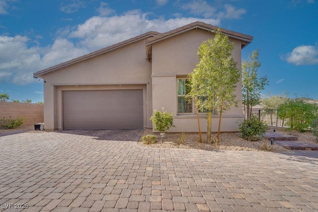 view of home's exterior with an attached garage, fence, stucco siding, and decorative driveway