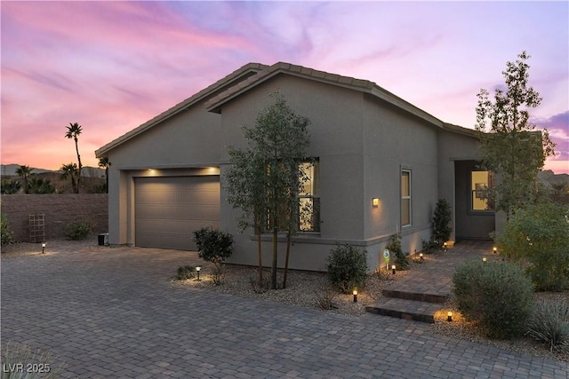view of home's exterior with stucco siding, an attached garage, and decorative driveway
