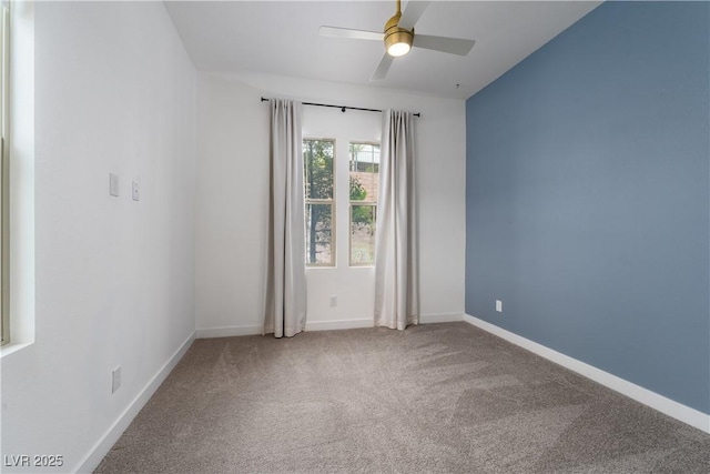carpeted spare room featuring baseboards and ceiling fan