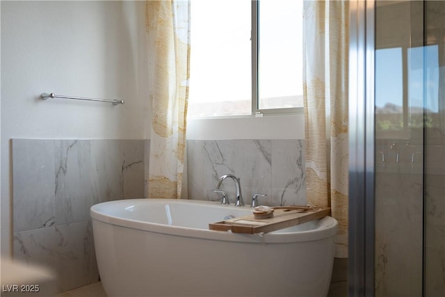 full bath featuring tile walls and a freestanding bath