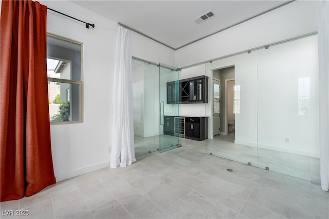 interior space featuring baseboards, visible vents, and light tile patterned floors