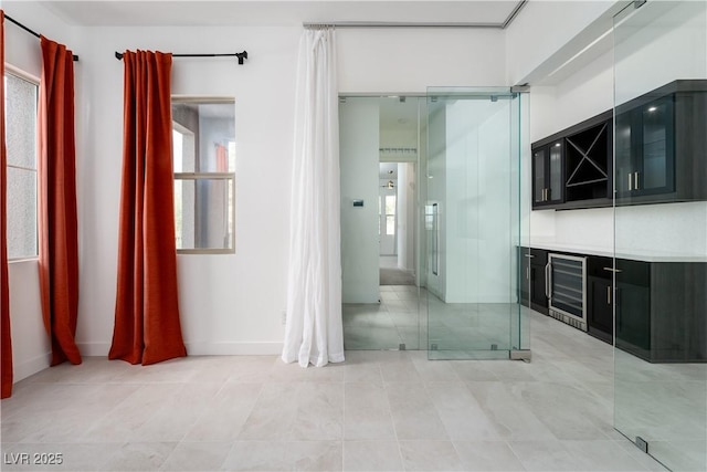 interior space with light tile patterned floors, baseboards, and wine cooler