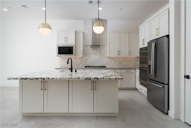 kitchen with tasteful backsplash, pendant lighting, wall chimney exhaust hood, appliances with stainless steel finishes, and light stone countertops