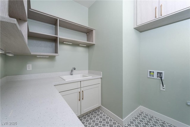 laundry area with light floors, a sink, hookup for a washing machine, baseboards, and cabinet space