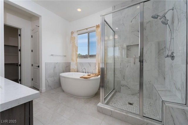 full bathroom featuring a soaking tub, vanity, and a marble finish shower